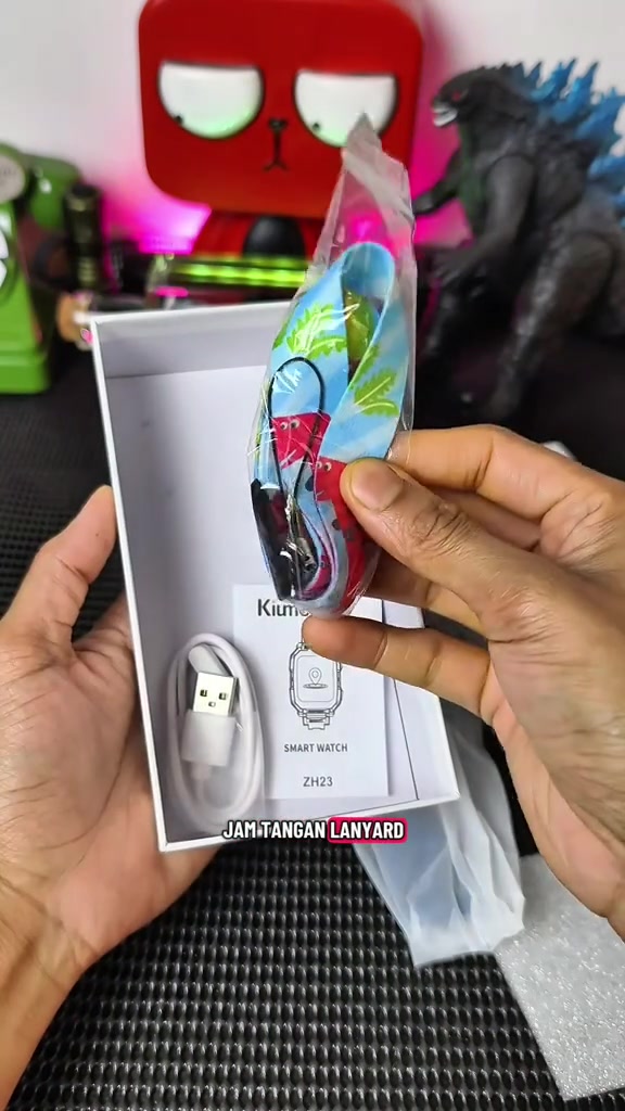 Kotak jam pintar kanak-kanak Kiumo dibuka, kelihatan tali lanyard, kabel pengecas USB dan manual