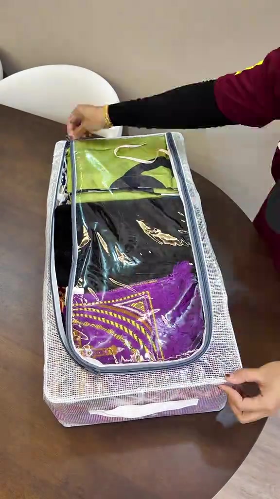Organizer fabrik berzip berisi kain lipat warna hijau dan ungu sedang ditutup zipnya