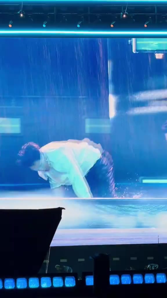 Một nghệ sĩ cúi người giữa mưa nước trên sân khấu đêm 2 Tinh Hà Say Hi Concert