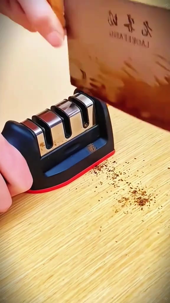 Pengasah pisau tarik tiga slot di atas papan kayu dengan parang di atasnya dan habuk logam bertaburan di sebelah