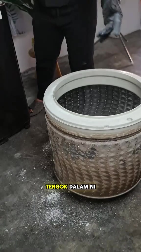 Drum mesin basuh yang dikeluarkan dari badan mesin, dinding luar diselaputi kerak perang tebal