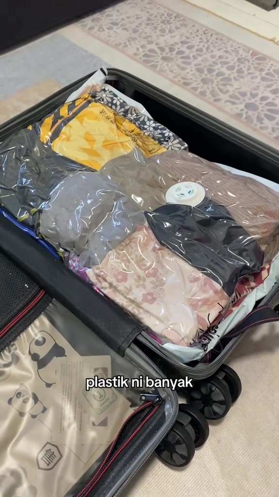 Beg vakum berisi baju lipat dimuatkan kemas ke dalam bagasi beroda