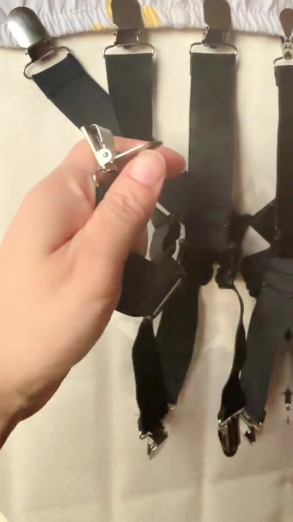 Tangan memegang klip logam pada tali elastik hitam sheet strap yang dicantum ke tepi cadar