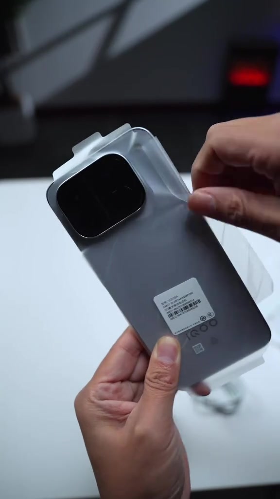 Mặt lưng iQOO Neo 12 còn lớp nilon bảo vệ và tem nhãn mã vạch, cụm camera vuông nằm góc trên