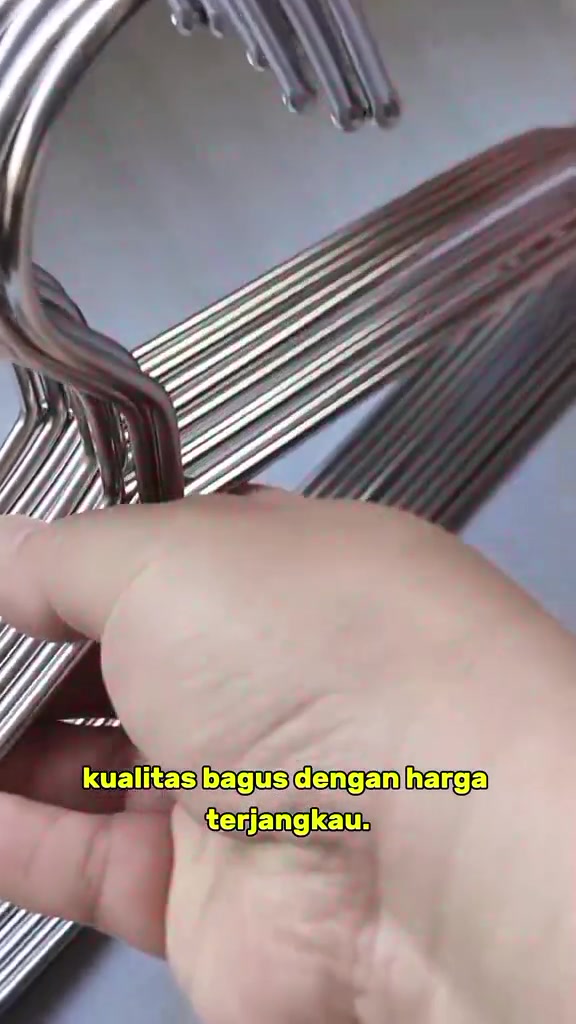 Hook hanger stainless steel berkilat dipegang tangan, nampak batang besi berganda dari dekat