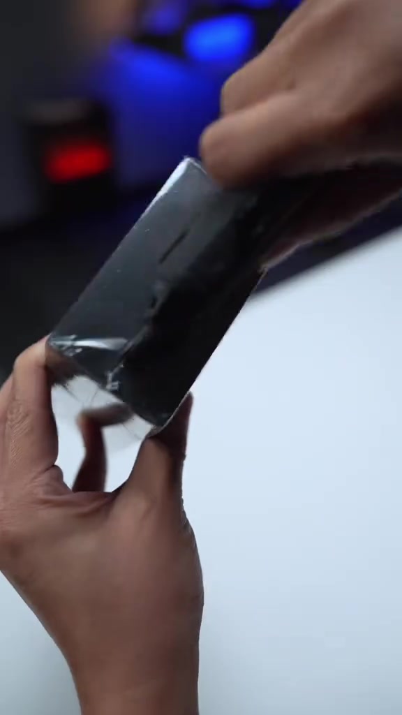 Hai tay đang xé lớp seal nilon trên hộp iQOO Neo 12 màu đen