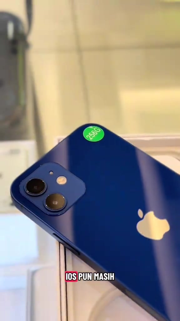 Bahagian belakang iPhone biru dengan pelekat bulat hijau bertulis 256G