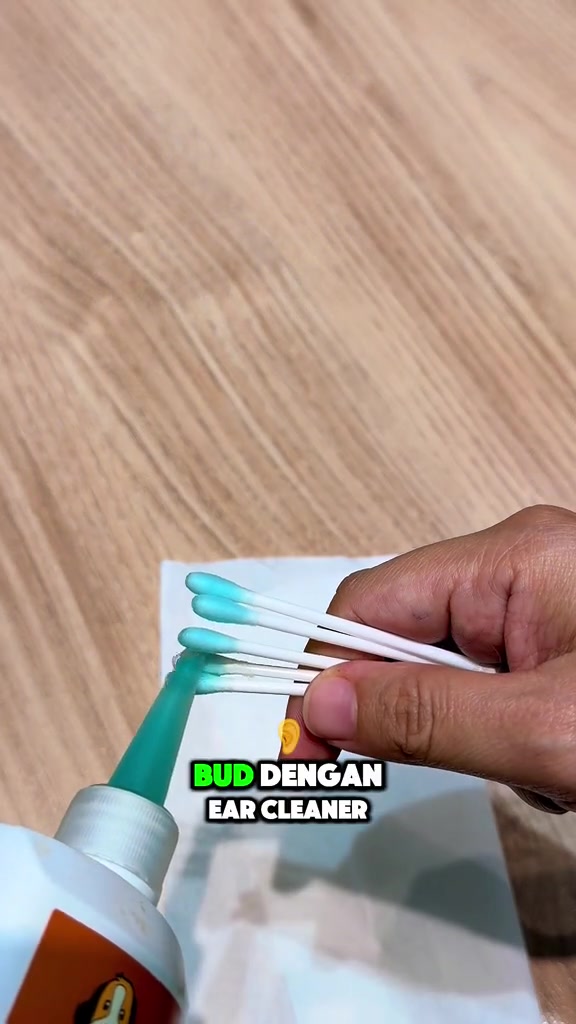 Tangan memegang beberapa cotton bud berhujung biru selepas dititik ear cleaner dari muncung botol hijau