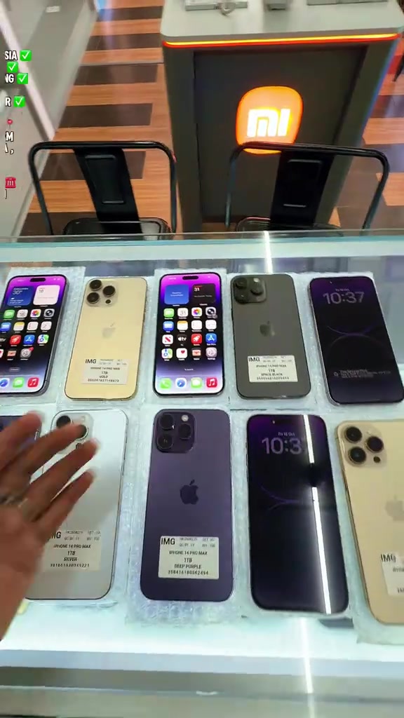 Kaunter kedai telefon dilihat dari atas dengan deretan iPhone 14 Pro Max pelbagai warna berpelekat stok kedai pada setiap unit