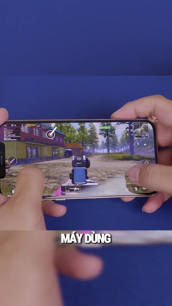 iPhone 12 Pro Max cầm ngang hai tay đang chơi game bắn súng góc nhìn thứ ba, khung cảnh game hiển thị trọn màn hình