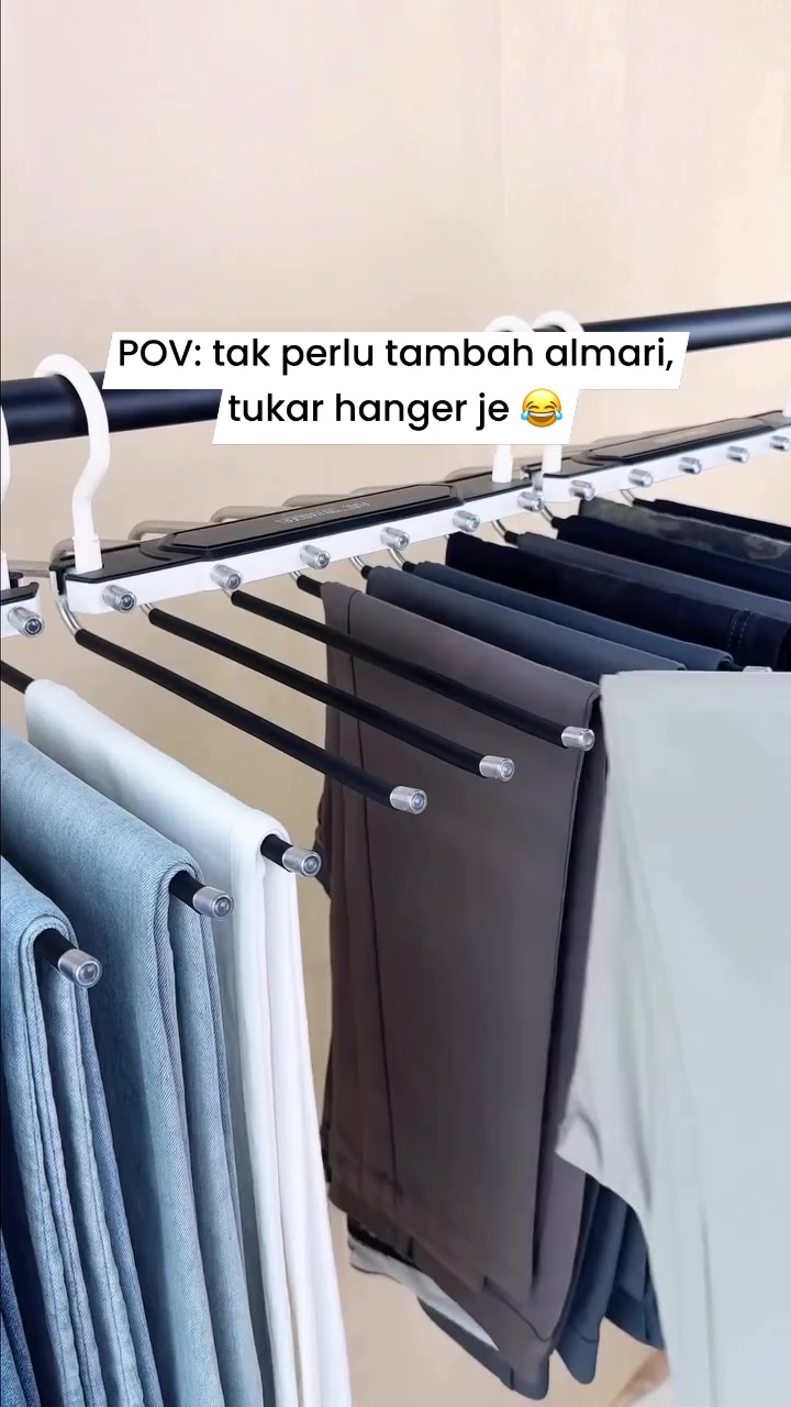 Hanger seluar berrod hitam tergantung pada rail dengan beberapa helai seluar tergantung kemas sebelah-menyebelah