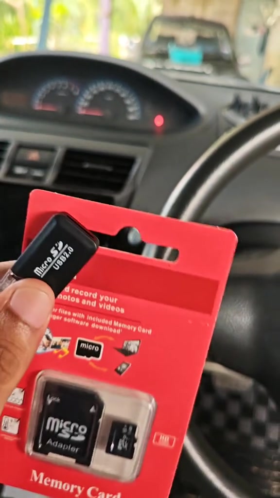 Pek kad tanpa jenama dan pembaca USB 2.0 dipegang dalam kereta dengan papan pemuka kelihatan di latar