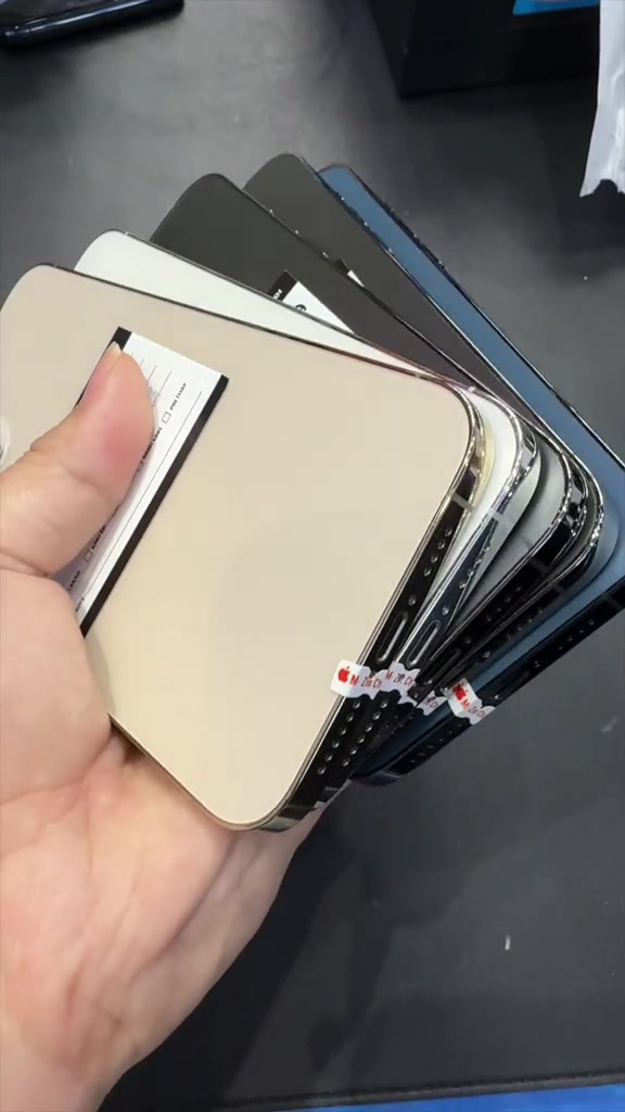 Xếp quạt năm chiếc iPhone 12 Pro Max cũ nhìn nghiêng từ phía lưng, tem niêm phong còn dán ở cạnh máy