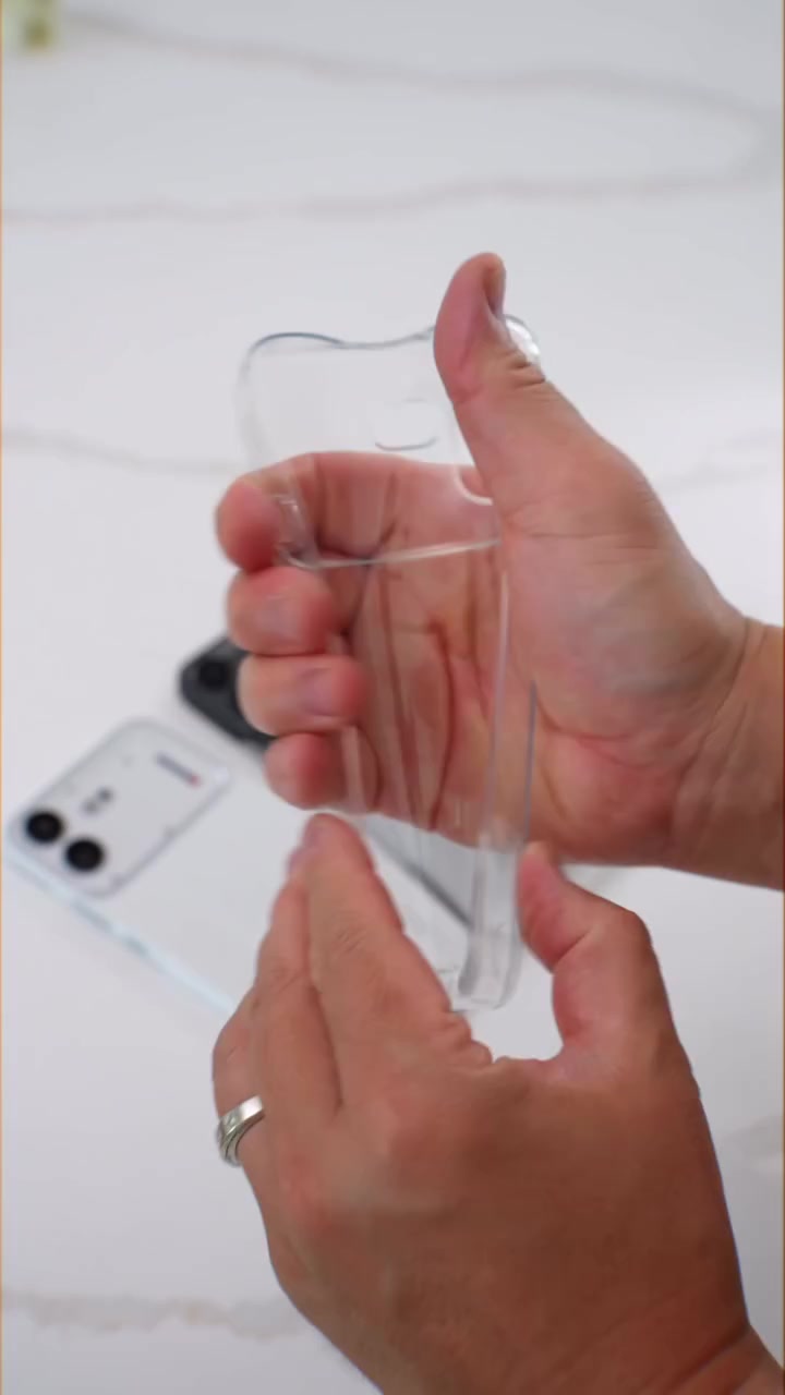 Case lutsinar bawaan Nothing Phone (4b) dipegang di tangan, dengan unit telefon di latar belakang