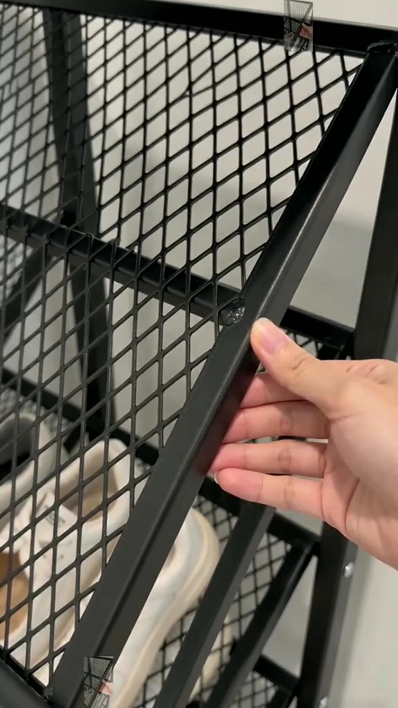 Tangan menyentuh permukaan mesh berlubang rak kasut besi hitam