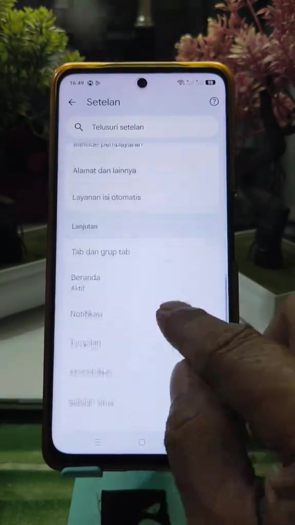 Skrin tetapan Android pada telefon yang dipegang, menunjukkan menu Setelan