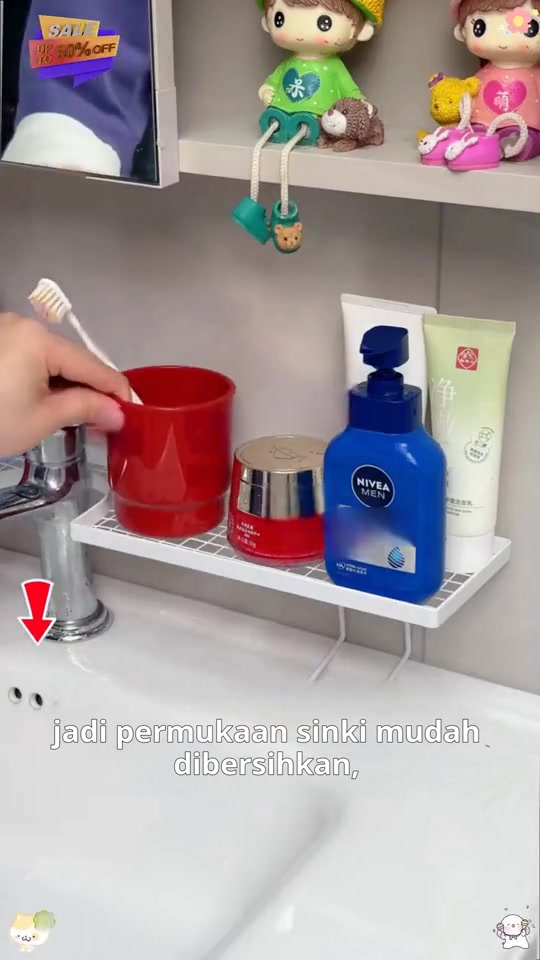 Rak grid putih melintang di belakang paip sinki memegang cawan, balang dan botol