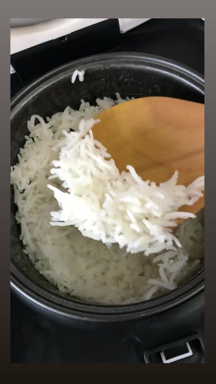 Nasi putih dalam periuk dalam non-stick dicebis menggunakan centong kayu