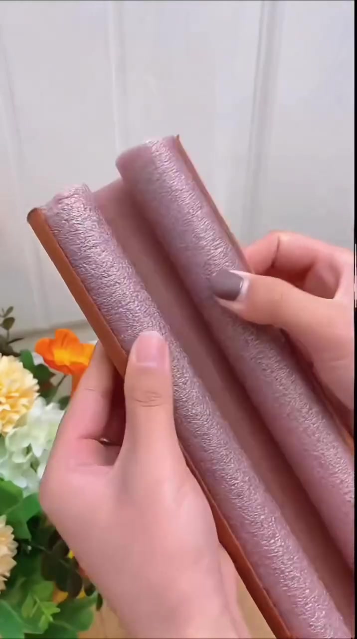 Dua tangan memegang draft stopper foam twin-tube warna coklat sebelum dipasang