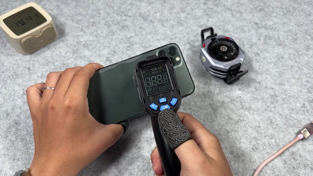 Súng đo nhiệt độ hồng ngoại chĩa vào lưng một chiếc iPhone màu xanh rêu
