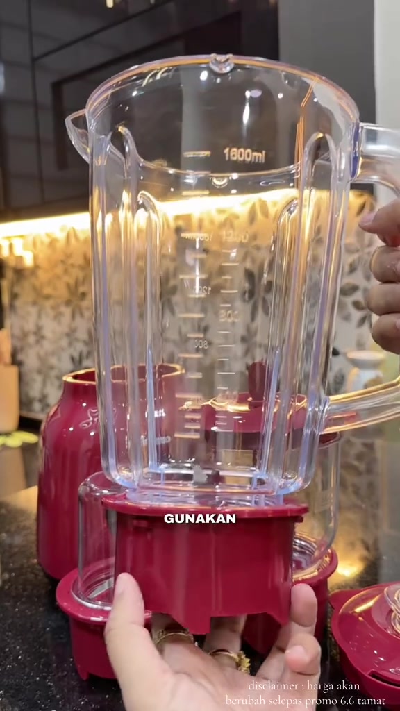Jar blender besar 1,600ml dengan garisan sukatan pada dinding jar, dipegang tangan di atas tapak motor merah