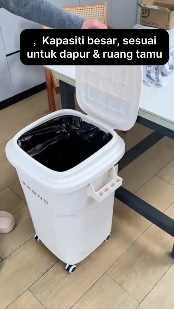Tong sampah putih kapasiti besar beroda dengan pemegang sisi dan penutup terbuka, diletakkan sebelah meja makan