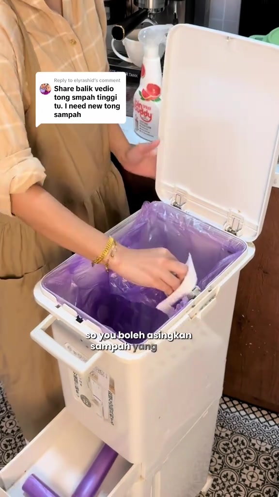 Tangan memasukkan sisa ke ruang atas tong sampah sorting dua tingkat berwarna putih berlapis beg plastik ungu, laci bawah terbuka