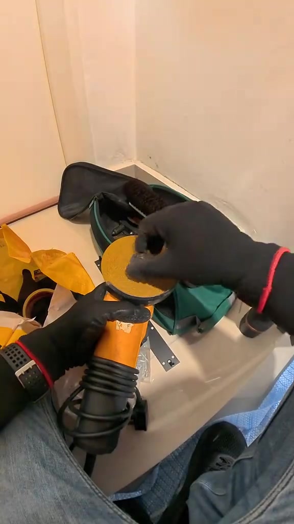 Alat pemasang di atas meja: mesin pengisar sudut berwarna jingga, beg alat dan plat pemasangan smart lock