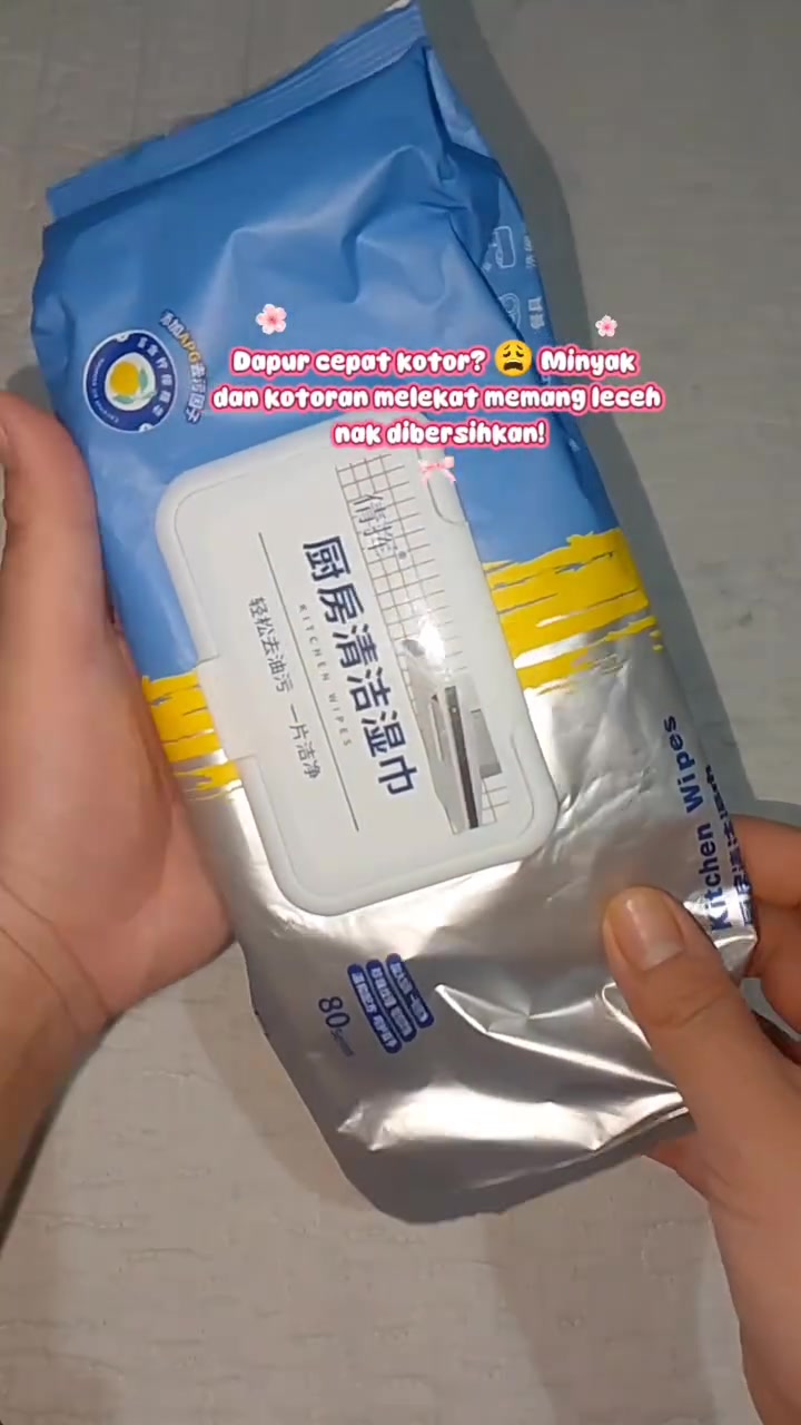 Tangan memegang pek tisu basah dapur biru-perak berlabel 80 keping