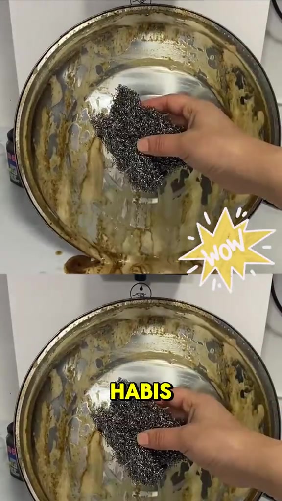 Tangan memegang berus dawai di atas permukaan stainless yang berlapis kerak minyak kuning tebal