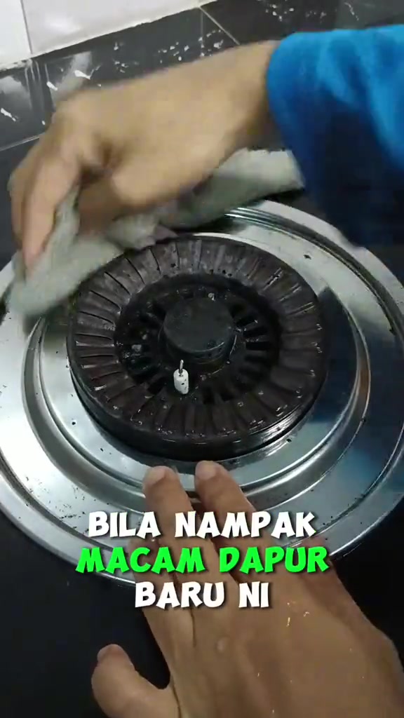 Tangan mengelap burner dapur gas yang sudah bersih dengan kain selepas memasak