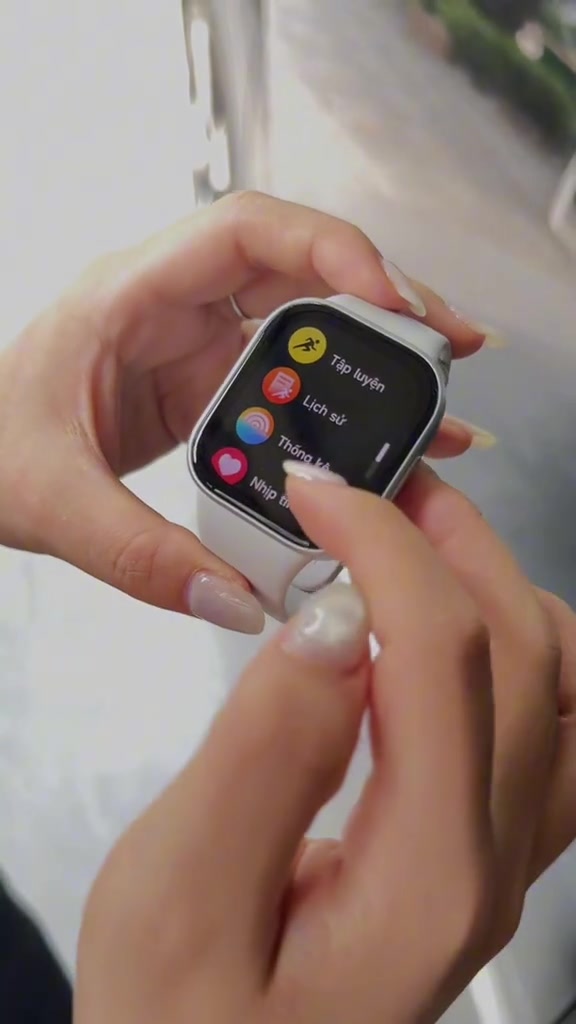Đồng hồ Redmi Watch 6 mặt vuông dây trắng cầm trên tay, màn hình hiển thị menu tiếng Việt gồm Tập luyện, Lịch sử, Thống kê, Nhịp tim
