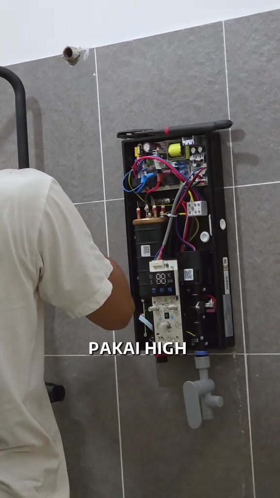 Bahagian dalam water heater terbuka menunjukkan wayar, papan litar dan komponen pemanas semasa pemasangan