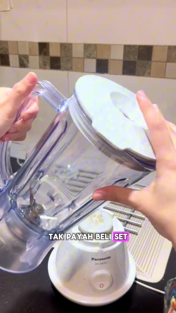 Tangan mengangkat jar blender Panasonic keluar dari tapak motor putih, menunjukkan jar boleh dibuka asing