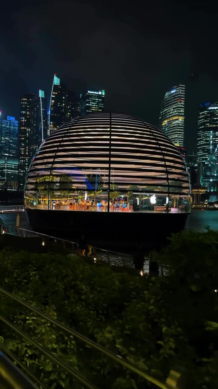 Kedai Apple Marina Bay Sands berbentuk kubah bercahaya pada waktu malam dengan latar pencakar langit Singapura