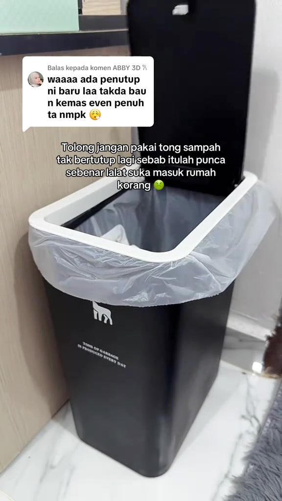 Tong sampah slim hitam dengan penutup terbuka dan beg plastik kelabu dilipat kemas di bibir tong putih