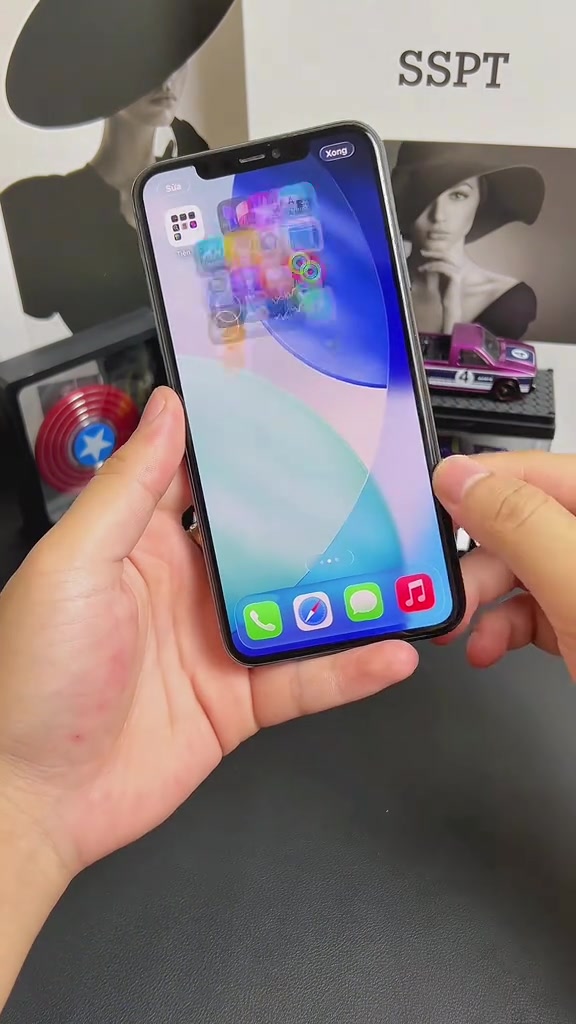 Một tay cầm chiếc iPhone đang mở màn hình chính với các icon ứng dụng