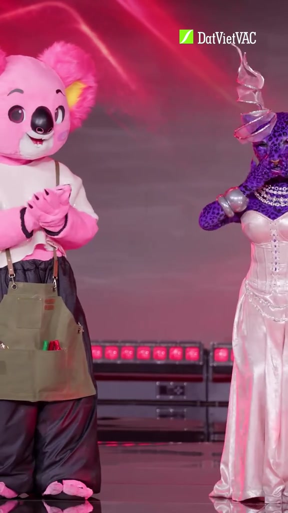 Koalaoke mặc tạp dề xanh olive vỗ tay cạnh Báo Berry váy trắng corset trên sân khấu ánh hồng