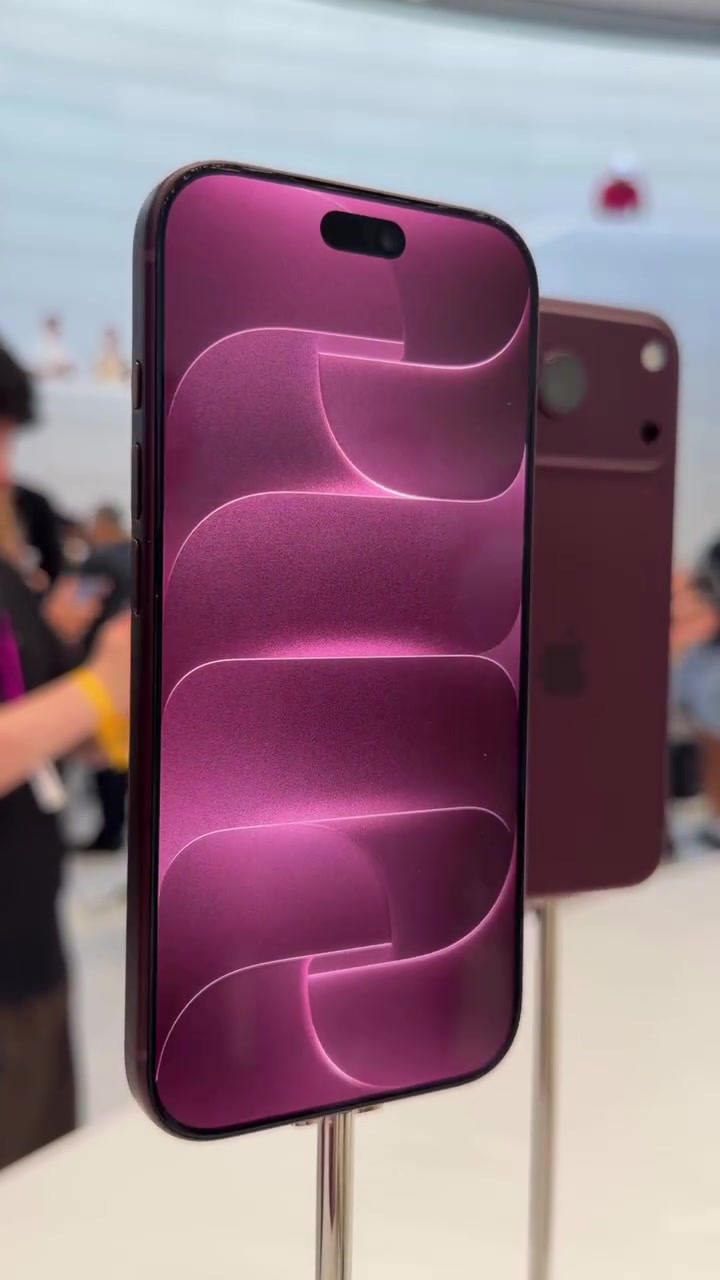 iPhone 18 Pro warna burgundy dipamerkan pada stand di dalam kedai Apple dengan orang ramai kabur di latar