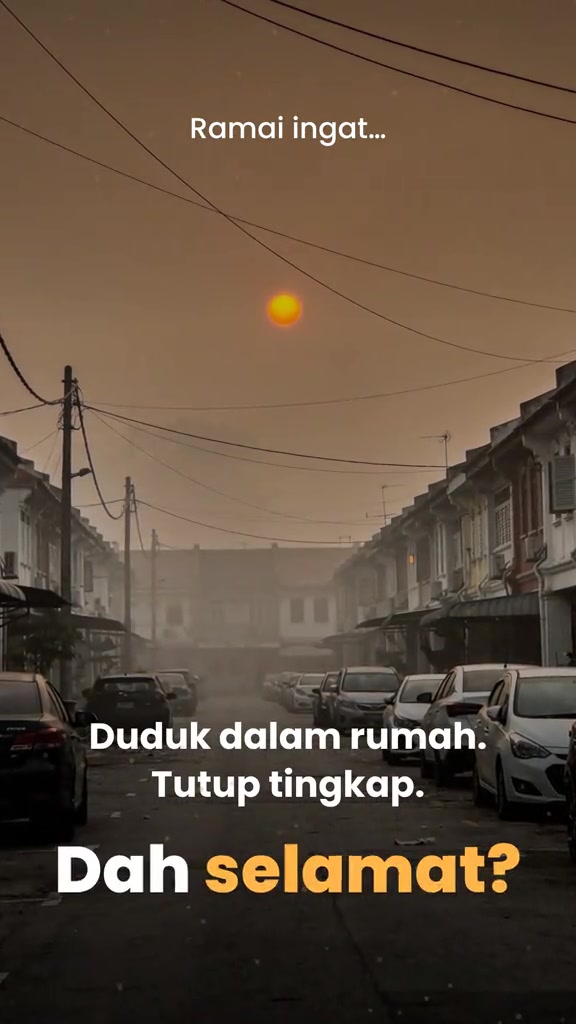 Jalan perumahan diselubungi jerebu tebal dengan matahari kelihatan jingga di langit berkabus