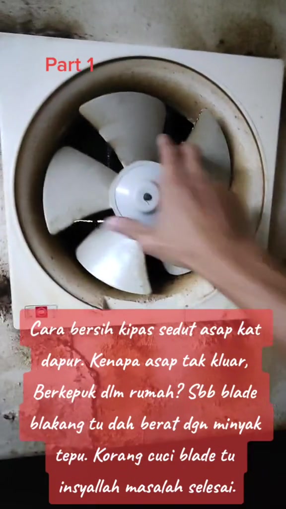 Kipas exhaust dapur dengan bilah kekuningan berminyak sedang dibuka dengan tangan untuk dicuci