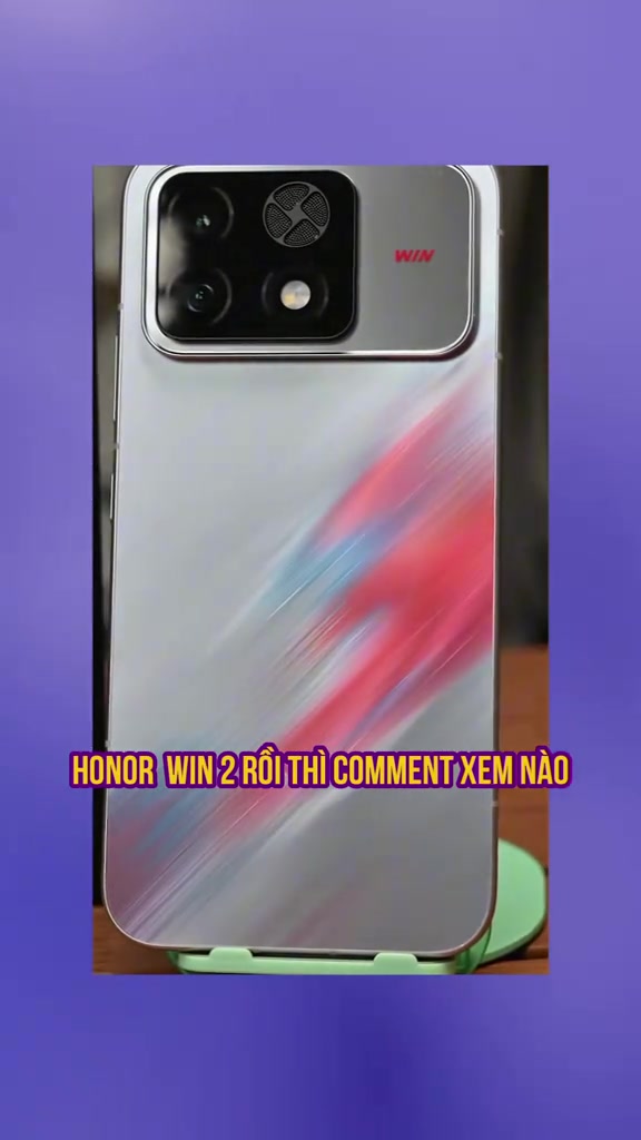 Mặt lưng bạc họa tiết vệt đỏ của điện thoại Honor WIN 2 đặt trên kệ xanh, thấy rõ lưới quạt tròn trong cụm camera