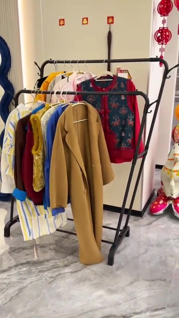 Rak baju besi dua bar berwarna hitam dengan roda, penuh baju dan jaket bergantung
