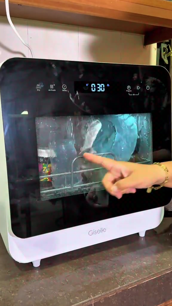 Mesin basuh pinggan tabletop Giselle berwarna putih di atas counter dapur, paparan digital menunjukkan kiraan masa 0:30 dan tangan menunjuk ke rak di dalam mesin