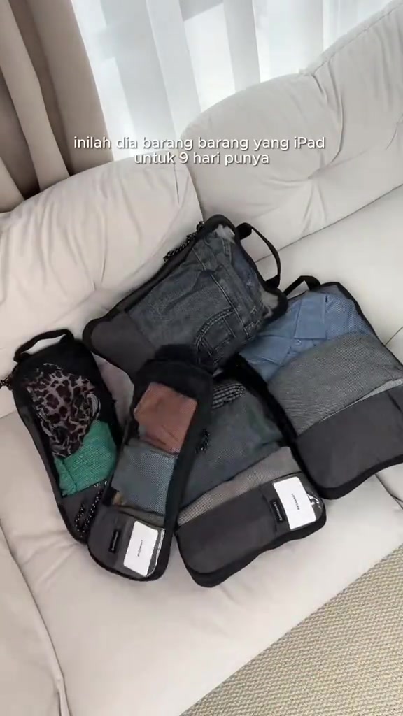 Lima packing cube hitam berisi pakaian tersusun atas sofa, cukup untuk pakaian sembilan hari