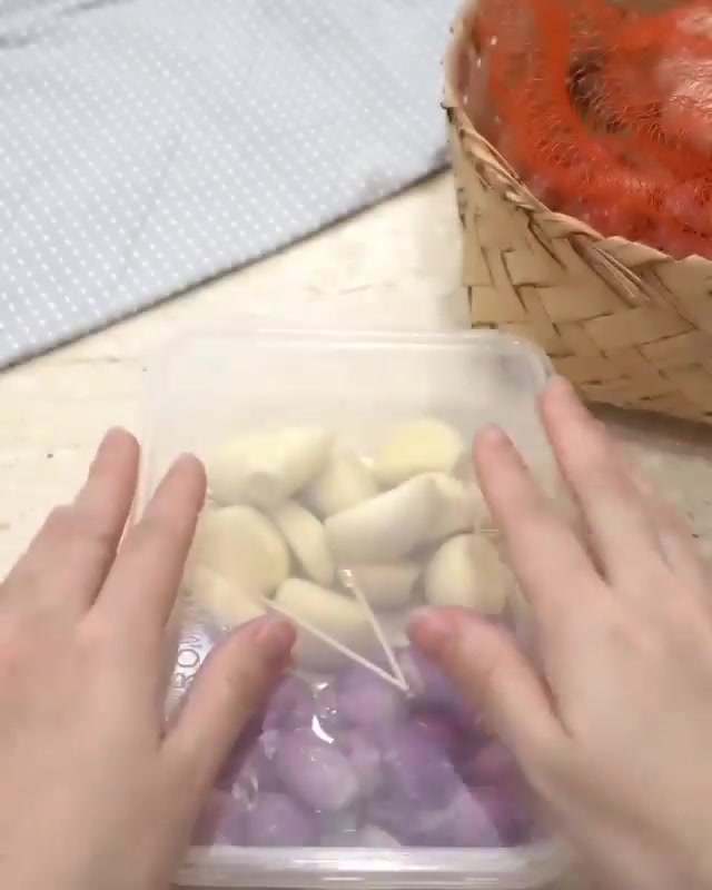 Dua tangan menutup penutup bekas plastik jernih yang berisi ulas bawang putih dan bawang merah yang sudah dikupas
