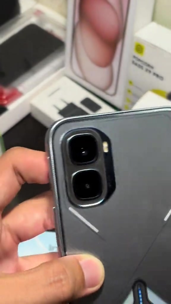 Modul kamera belakang Infinix GT 50 Pro warna kelabu gelap dipegang tangan, latar kotak telefon