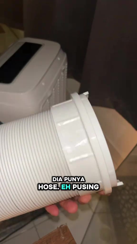 Tangan memegang hujung penyambung hose putih portable aircond