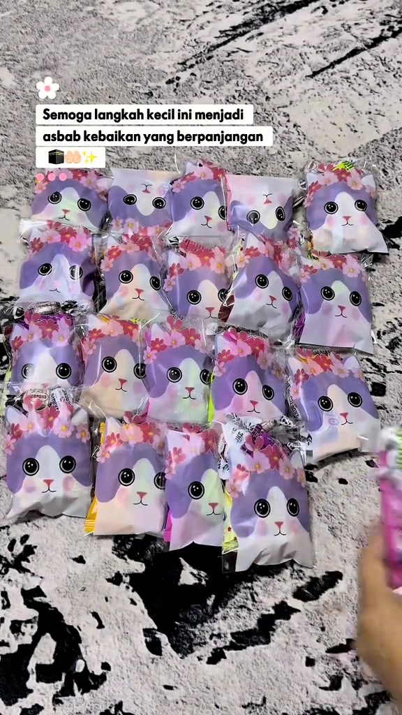 Deretan pouch goodies kecil bercorak comel tersusun rapi atas permaidani, siap untuk dibawa sebagai sadaqah