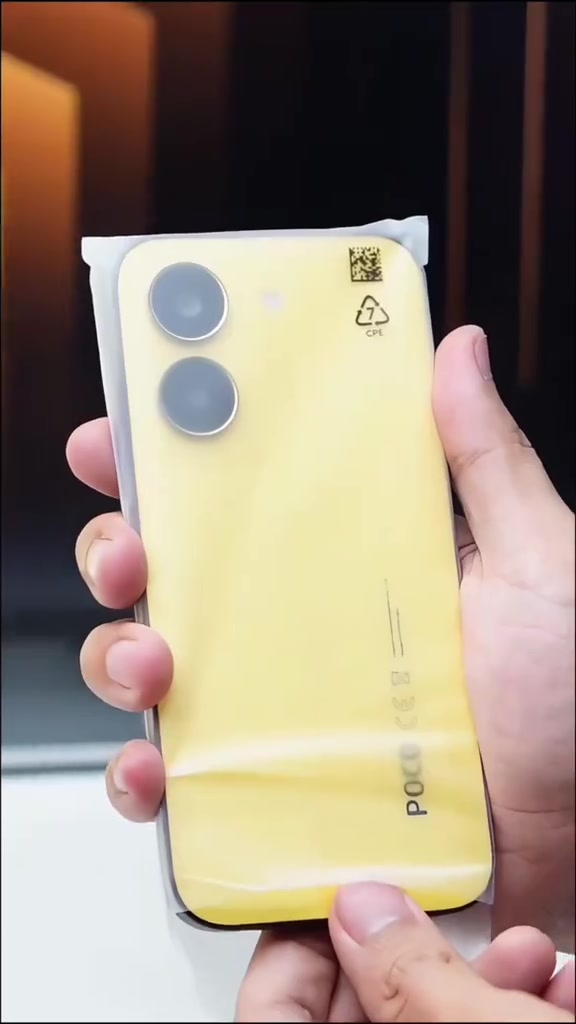 Bahagian belakang POCO X8 Pro warna kuning masih berbalut plastik perlindungan di tangan